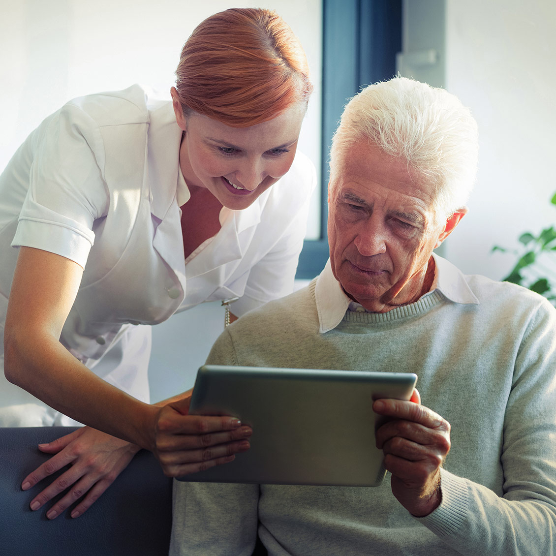 Female nurse showing medical report to senior man on digital tab
